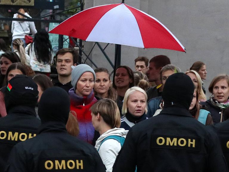 Omon-Polizisten bedrängen demonstrierende Frauen in Minsk am 08.09.2020, sie halten einen rotweißen Regenschirm über ihre Köpfe Omon-Polizisten bedrängen demonstrierende Frauen in Minsk am 08.09.2020, sie halten einen rotweißen Regenschirm über ihre Köpfe