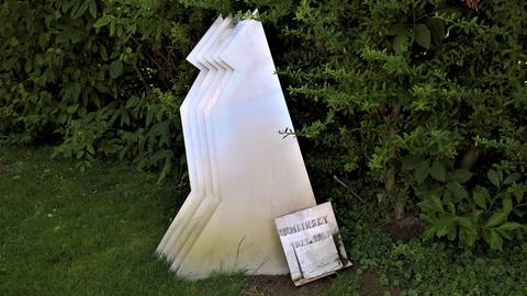 Auf einer Wiese zeigt sich die Grabstele von Alexander von Zemlinsky, die stilisiert wie ein wartender Hund aussieht.