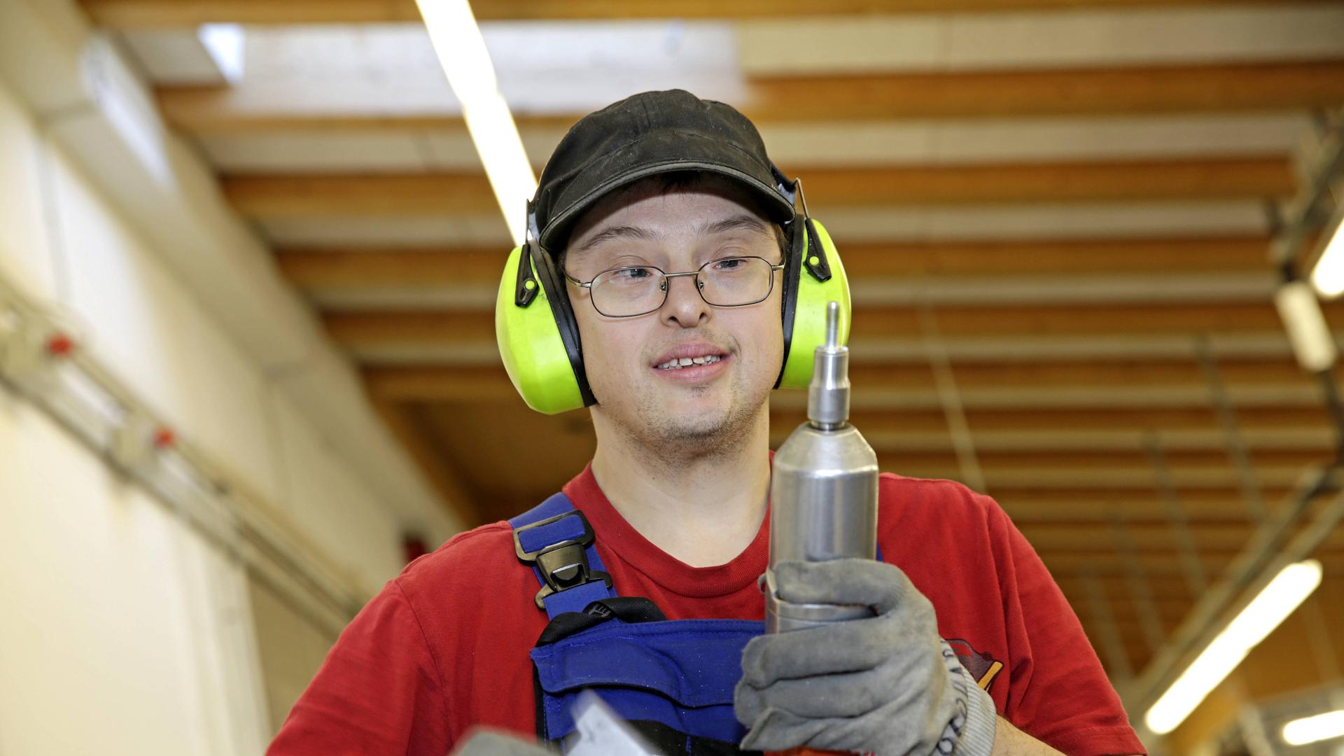 Ein junger Mann mit Down-Syndrom bei der Arbeit. Er ist Hand-Werker.