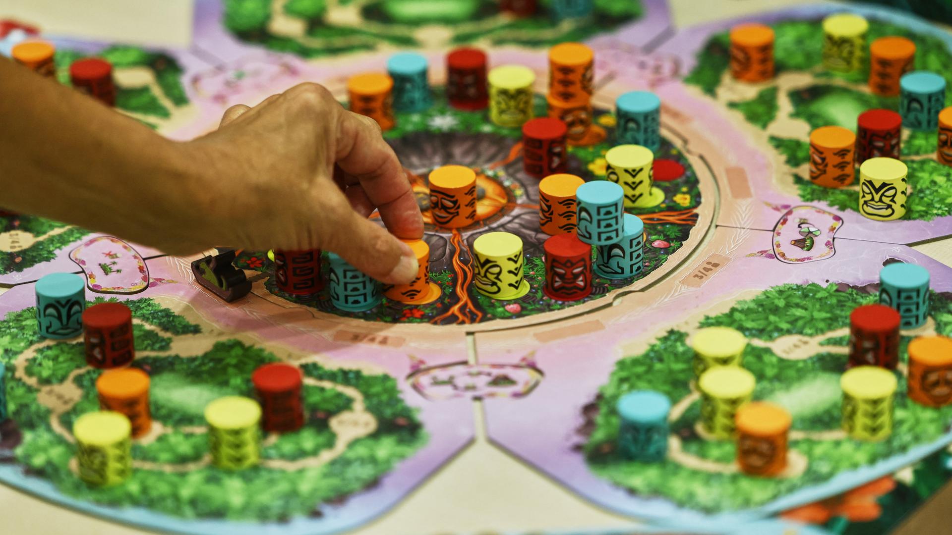 Ein Hand stellt einen Spielstein auf der Publikumsmesse "Spiel Essen" auf das Brettspiel "Kilauea". Ein Hand stellt einen Spielstein auf der Publikumsmesse "Spiel Essen" auf das Brettspiel "Kilauea".
