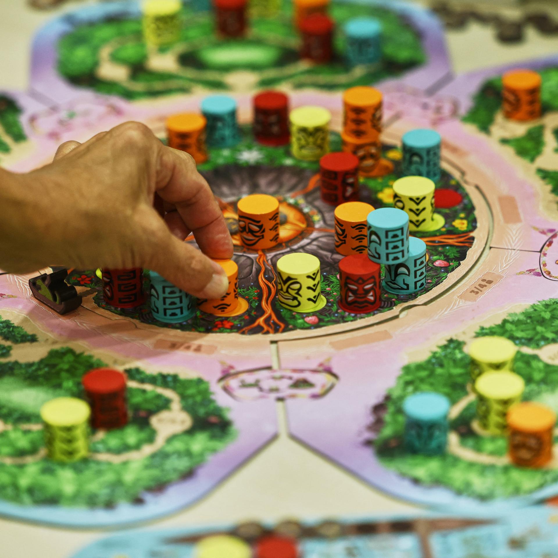 Ein Hand stellt einen Spielstein auf der Publikumsmesse "Spiel Essen" auf das Brettspiel "Kilauea".