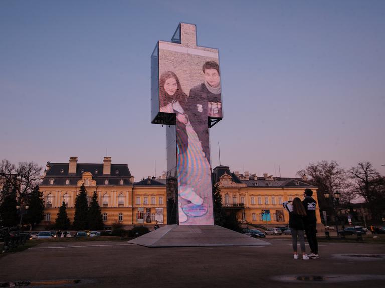 Zu sehen sind Jugendliche auf einem Platz im Zentrum von Sofia als Teil einer interaktiven Video-Installation namens "One Man" in Form einer 13 Meter hohen Statue. Sie stammt von Venelin Shurelov, einem zeitgenössischer Künstler.