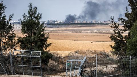 Blick auf ein zerstörtes Tor im Grenzzaun zwischen dem israelischen Kibbuz Kfar Aza und dem Gazastreifen. Im Hintergrund eine Rauchsäule.
