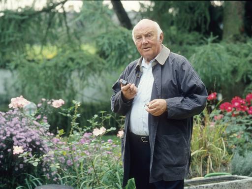 Kinderbuchautor Otfried Preußler steht auf einem Farbfoto von 1993 leger in einem Garten mit einem Diktiergerät in der Hand. 