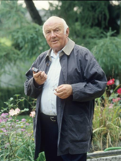 Kinderbuchautor Otfried Preußler steht auf einem Farbfoto von 1993 leger in einem Garten mit einem Diktiergerät in der Hand. 