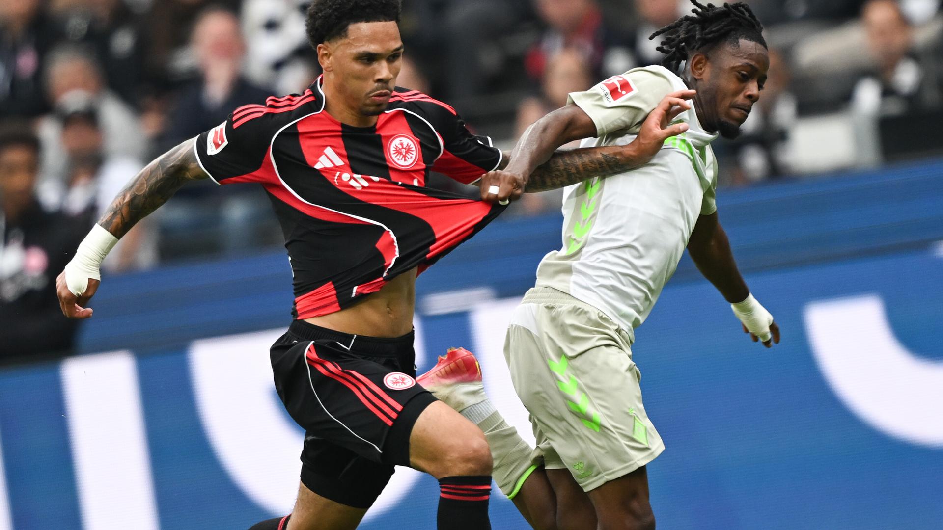 Beide Spieler rennen eng nebeneinander hinter dem Ball her, sie versuchen sich gegenseitig wegzudrücken und am Trikot zu ziehen. Beide Spieler rennen eng nebeneinander hinter dem Ball her, sie versuchen sich gegenseitig wegzudrücken und am Trikot zu ziehen.