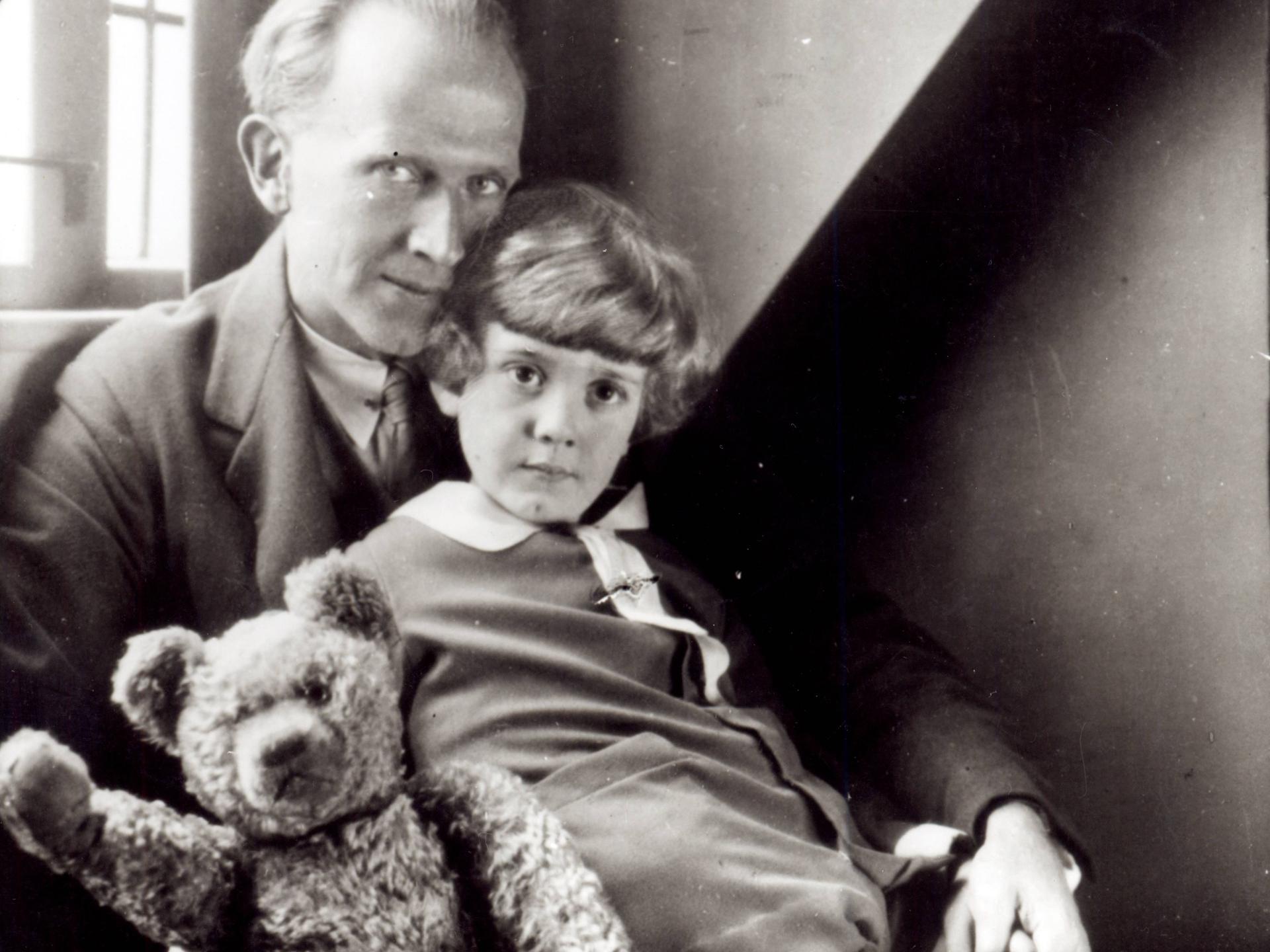 Schwarzweißfoto mit dem Autor A. A. Milne und sein Sohn Christopher Robin sowie die Plüschpuppe Winnie the Pooh.
