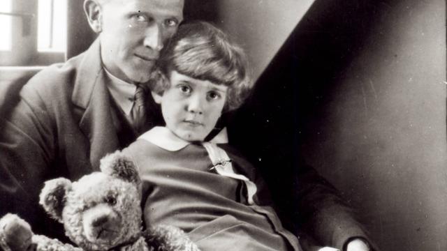 Schwarzweißfoto mit dem Autor A. A. Milne und sein Sohn Christopher Robin sowie die Plüschpuppe Winnie the Pooh.