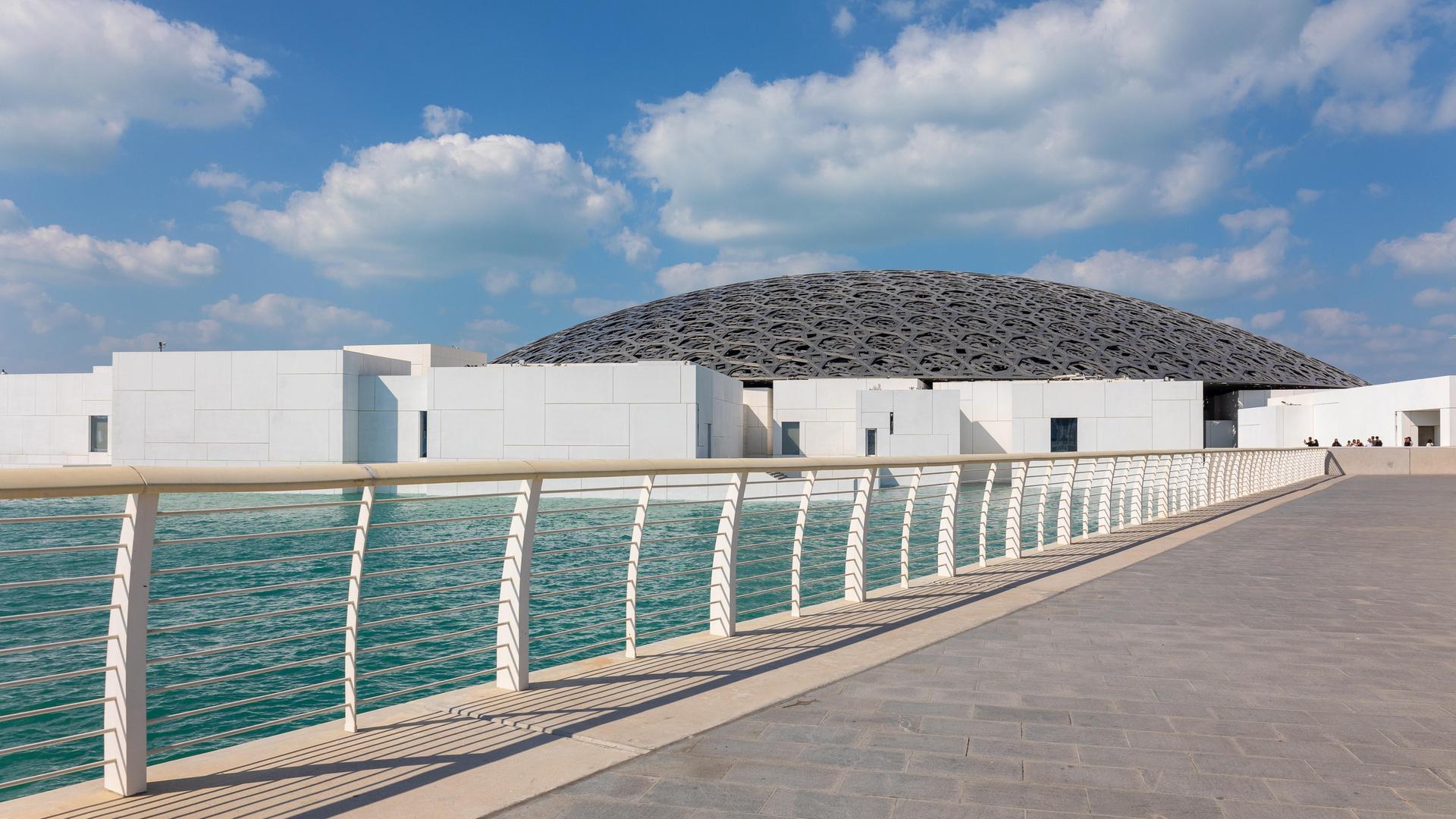 Das Kunstmuseum Louvre mit einem hochmodernen Bau in Abu Dhabi, zu dem eine Brücke am Meer führt Das Kunstmuseum Louvre mit einem hochmodernen Bau in Abu Dhabi, zu dem eine Brücke am Meer führt