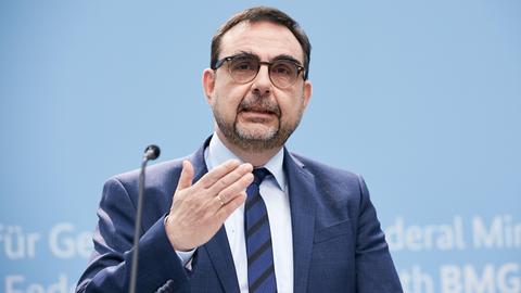 Klaus Holetschek, Bayerischer Staatsminister für Gesundheit und Pflege, steht bei einer Pressekonferenz hinter einem Rednerpult und gestikuliert mit der rechten Hand.