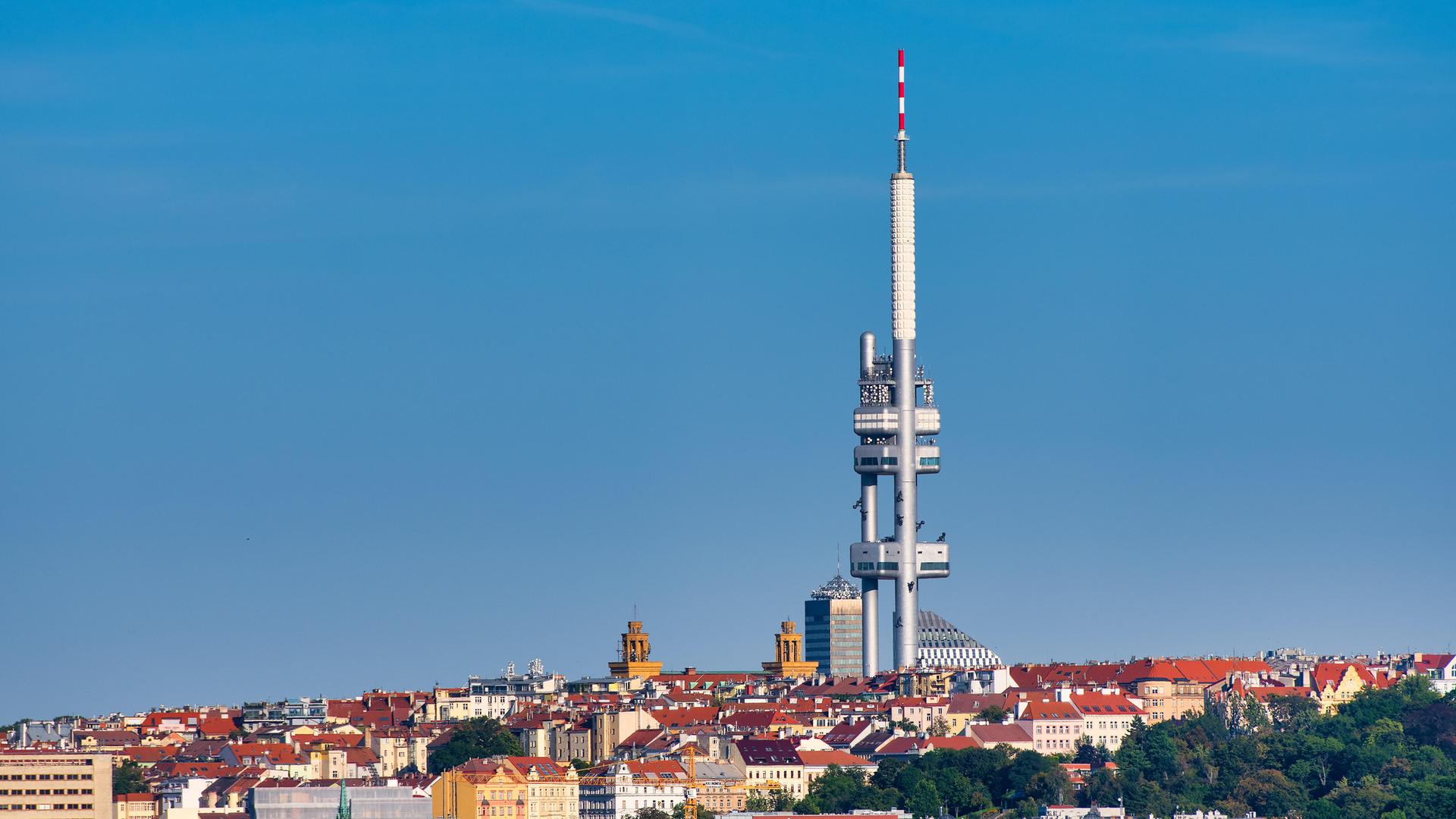 Ein zweiteiliger Fernsehturm ragt weit über die umgebenden Gebäude hinaus und hebt sich vor einem wolkenlosen Himmel ab.