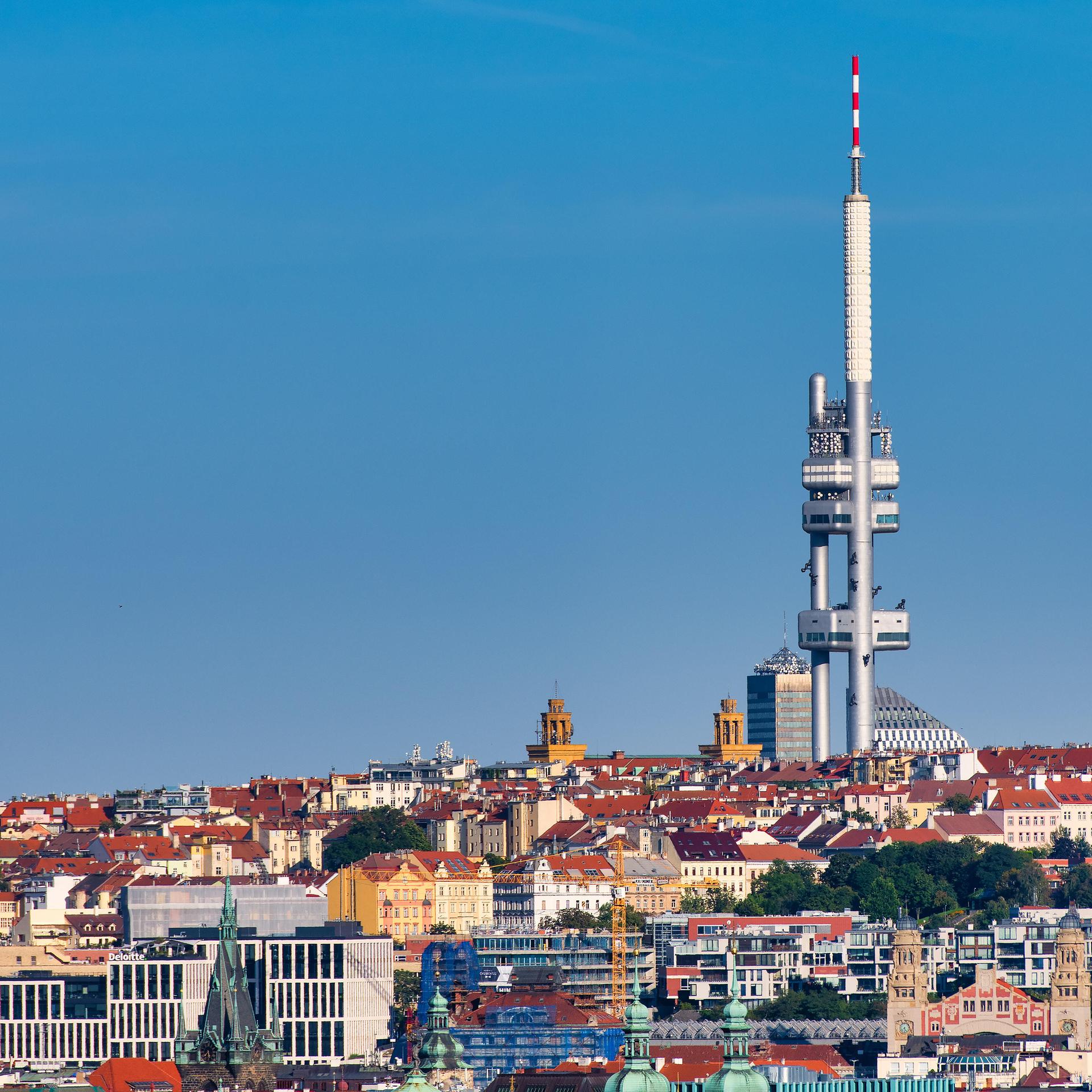 Ein zweiteiliger Fernsehturm ragt weit über die umgebenden Gebäude hinaus und hebt sich vor einem wolkenlosen Himmel ab.