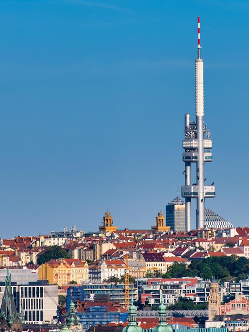Ein zweiteiliger Fernsehturm ragt weit über die umgebenden Gebäude hinaus und hebt sich vor einem wolkenlosen Himmel ab.