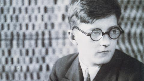 Der junge Dmitrij Schostakowitsch sitzt nachdenklich auf einem Stuhl. Undatiertes Foto aus der Sammlung  Bibliotheque-Musee de l'Opera Garnier, Paris.