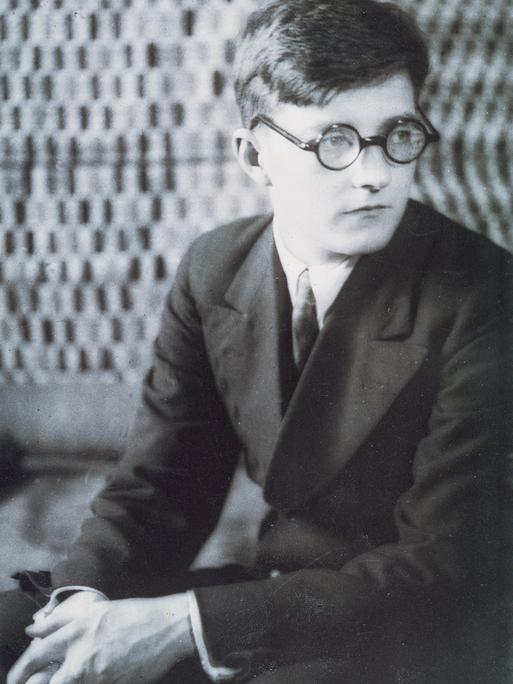 Der junge Dmitrij Schostakowitsch sitzt nachdenklich auf einem Stuhl. Undatiertes Foto aus der Sammlung  Bibliotheque-Musee de l'Opera Garnier, Paris.