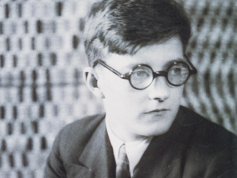 Der junge Dmitrij Schostakowitsch sitzt nachdenklich auf einem Stuhl. Undatiertes Foto aus der Sammlung  Bibliotheque-Musee de l'Opera Garnier, Paris.