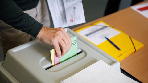 Ein Wähler wirft seine Stimmzettel in eine Wahlurne in einem Wahlraum.