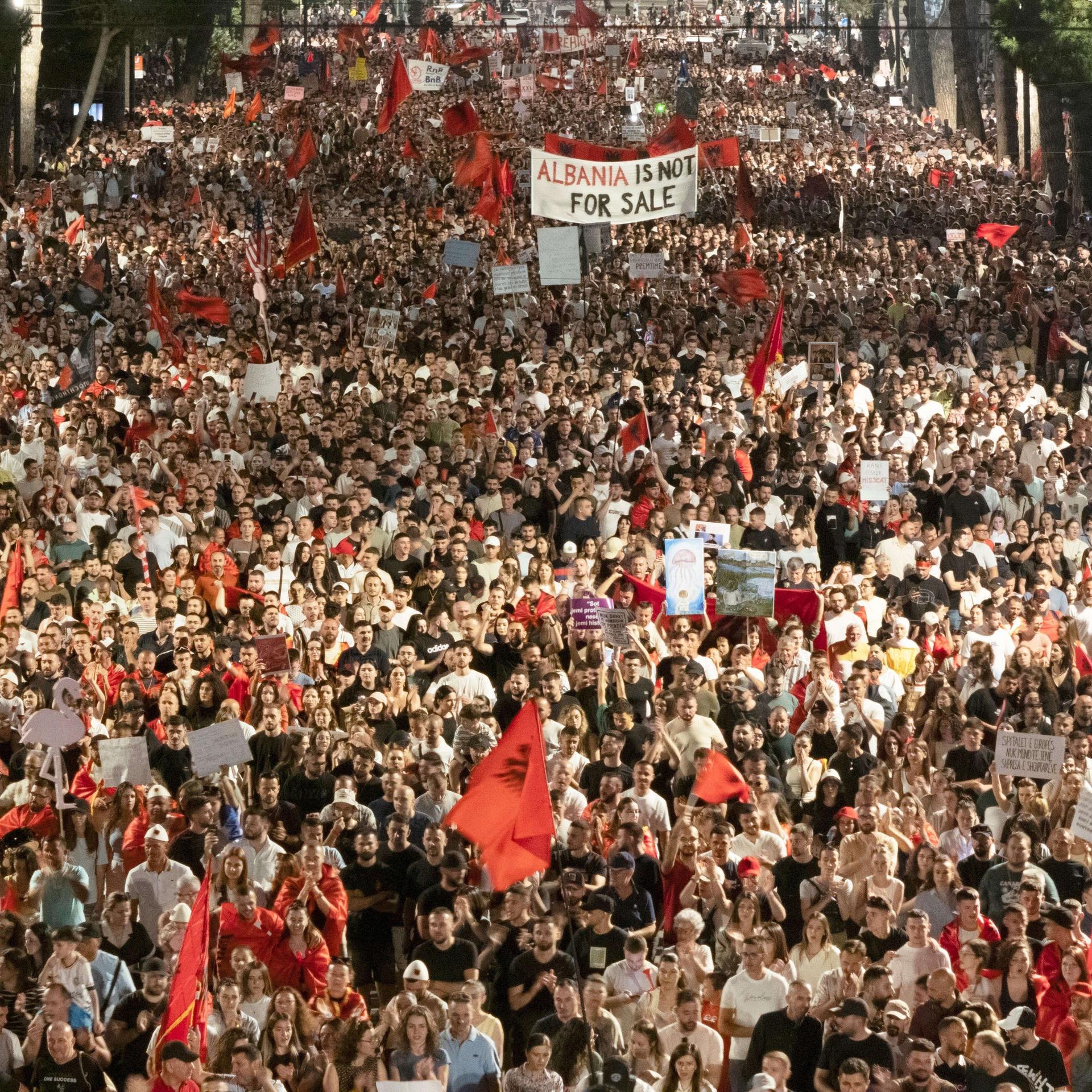 Eine große Demonstration mit vielen Teilnehmern. Man sieht viele rote albanische Flaggen und in der Mitte ein großes Protest-Schild. Es trägt die Aufschrift "Albania ist not for sale" - also "Albanien ist nicht zu verkaufen". 