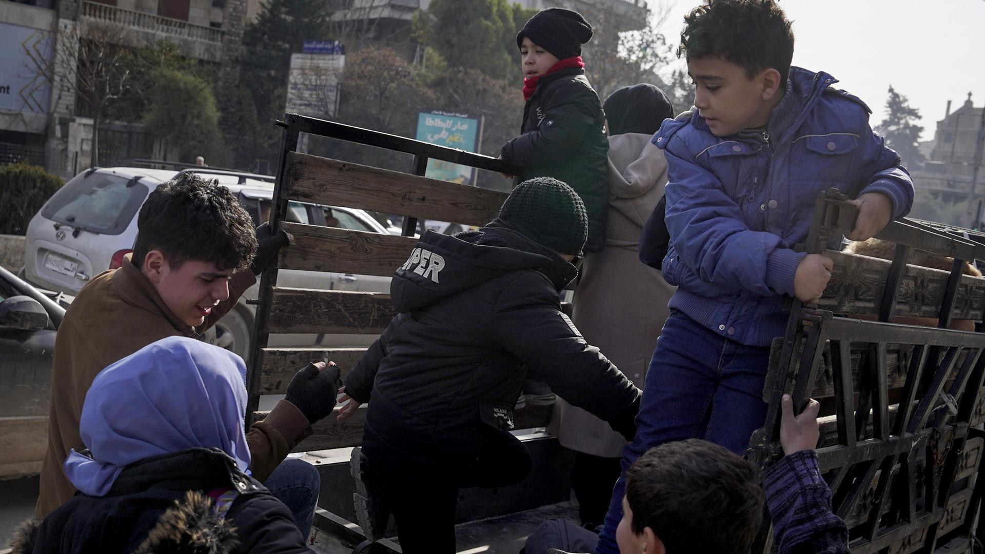 Eine Familie mit Kindern klettert auf einen Lastwagen.