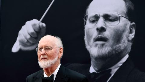 Der Dirigent und Filmkomponist John Williams mit einem Foto von ihm im Hintergrund.  