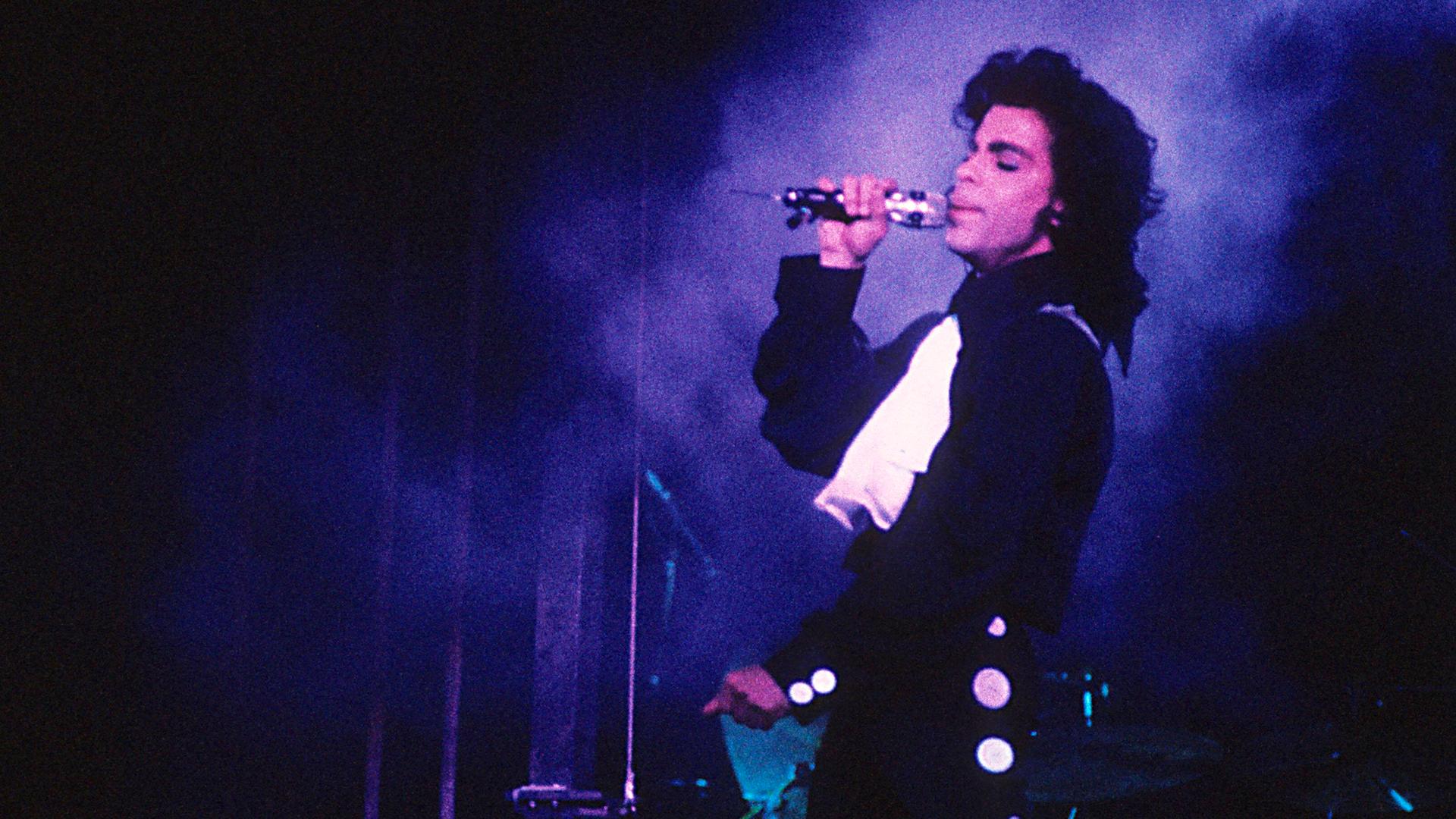 Prince singt auf der Bühne in purpurem Licht.
