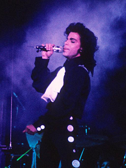 Prince singt auf der Bühne in purpurem Licht. Prince singt auf der Bühne in purpurem Licht.