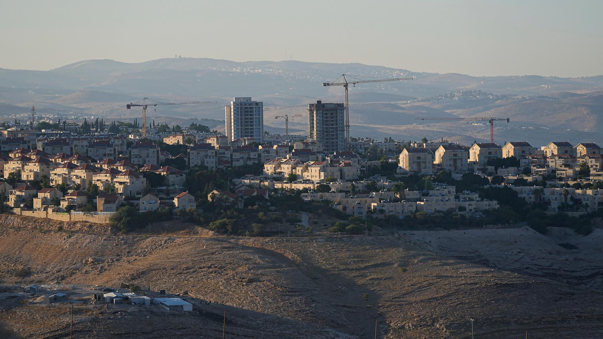 Blick auf die israelische Siedlung Male Adumim im Juni 2023. Man sieht neben mehreren kleineren Häusern zwei Hochhäuser und einige Baukräne.