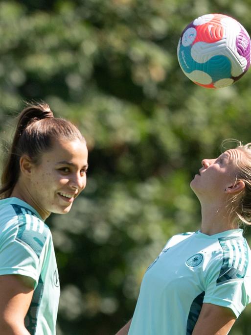 Großbritannien, Watford: Fußball-Nationalmannschaft, Frauen-EM 2022. Deutschlands Alexandra Popp (r) spielt neben Lena Sophie Oberdorf einen Kopfball beim Training.