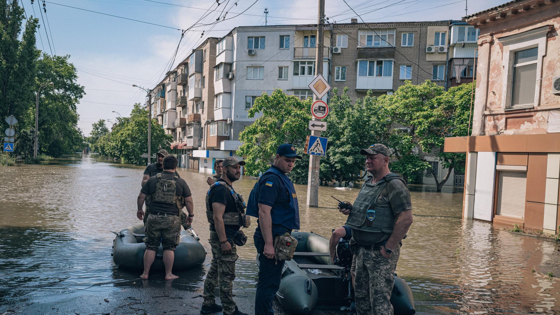 Mitarbeiter eine Hilfsorganisation stehen in Cherson in der Ukraine auf einer überfluteten Straße