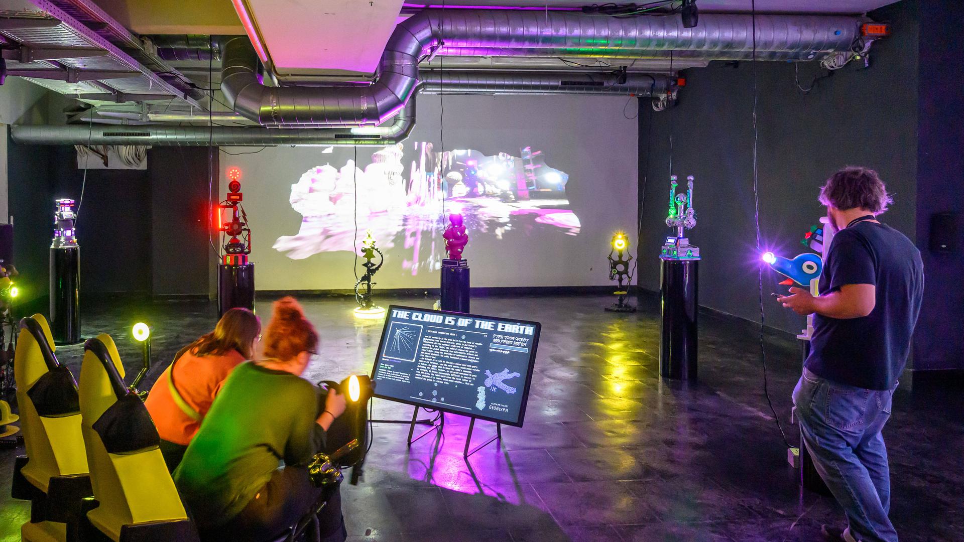 Besucherinnen der Ars Electronica sitzen in einem abgedunkelten Raum vor einem Bildschirm.