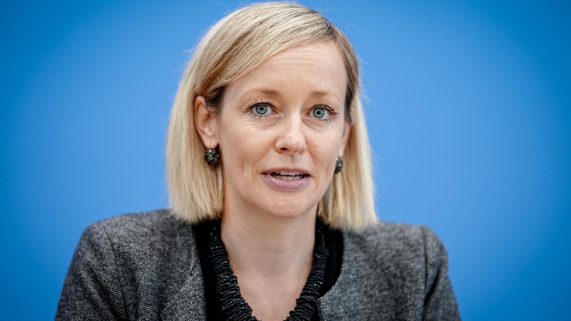 Louisa Specht-Riemenschneider, Bundesbeauftragte für Datenschutz und Informationsfreiheit, schaut direkt in die Kamera. Sie sitzt vor einem blauen Hintergrund.