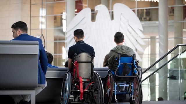 Besucher im Rollstuhl beobachten die Debatte des Deutschen Bundestages.