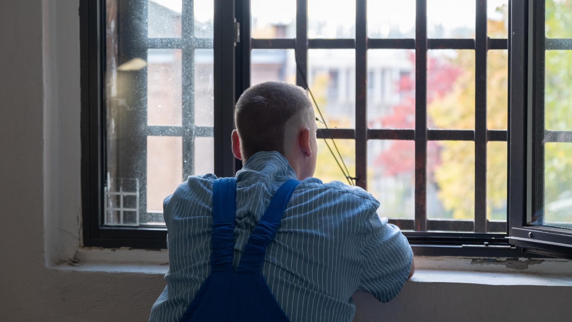 Der Häftling schaut es dem vergitterten Fenster seiner Zelle. Man sieht ihn von hinten.