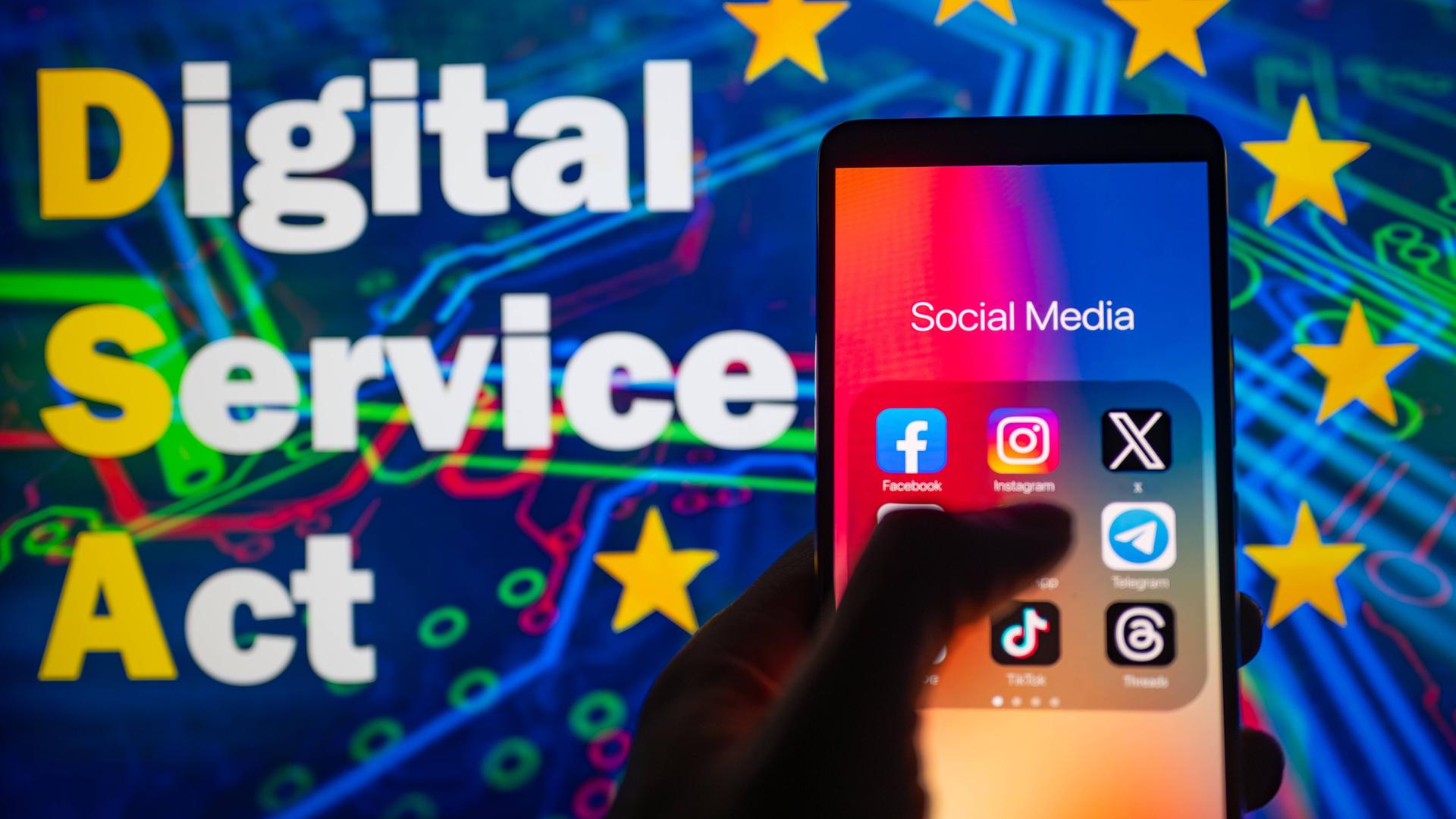 Ein Smartphone mit Social-Media-Anwendungen, im Hintergrund eine Grafik zum Digital Service Act der EU