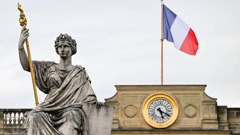 Die Statue der Marianne vor dem Gebäude der Nationalversammlung in Paris, auf dessen Dach die französische Flagge weht.