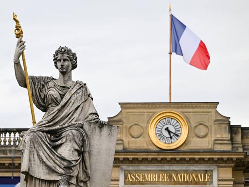 Die Statue der Marianne vor dem Gebäude der Nationalversammlung in Paris, auf dessen Dach die französische Flagge weht 