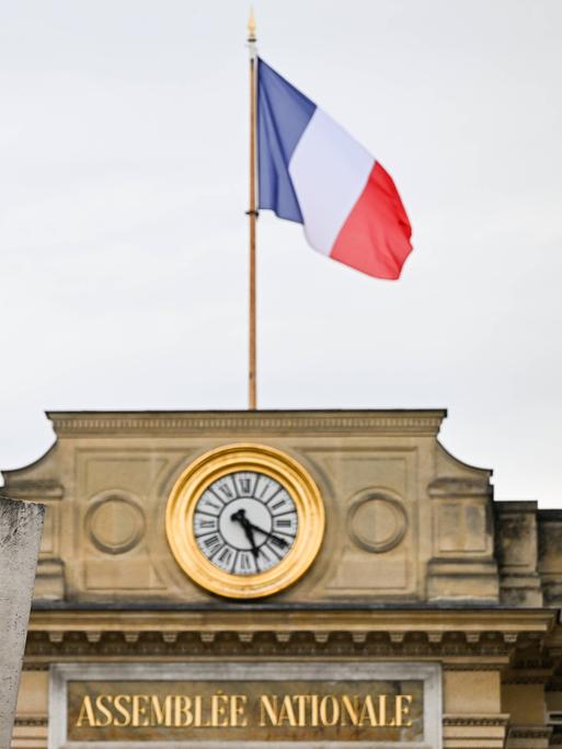 Die Statue der Marianne vor dem Gebäude der Nationalversammlung in Paris, auf dessen Dach die französische Flagge weht 