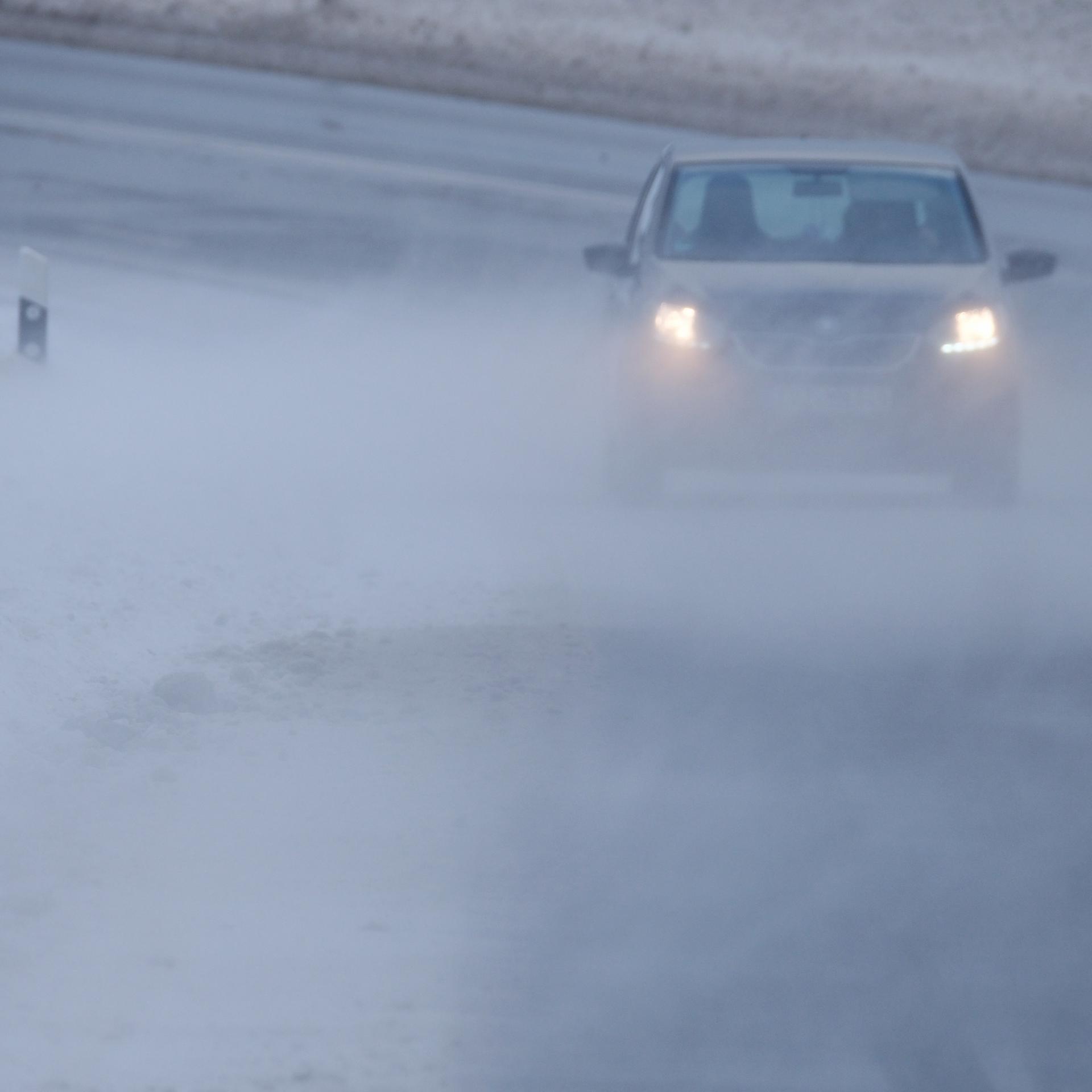 Sachsen, Annaberg-Bchholz: Schnee wird über eine Straße geweht, auf der ein Auto fährt. 