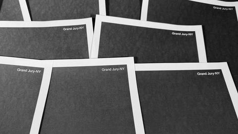 Mehrere komplett geschwärzte Unterlagen liegen nebeneinander. Oben rechts steht jeweils "Grand Jury NY" in weiß auf schwarz.