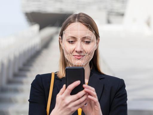 Geschäftsfrau bei Nutzung ihres Mobilfunkgerätes mit Gesichtserkennung. 