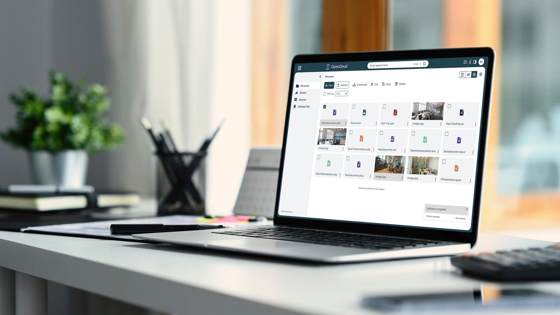 Auf einem Schreibtisch steht ein aufgeklappter Laptop. Der Bildschirm zeigt mehrere Kacheln mit Open-Source-Programmen.