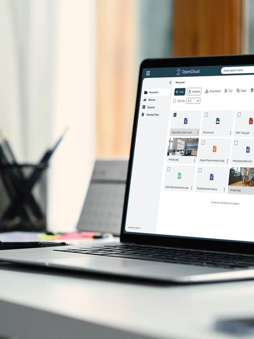 Auf einem Schreibtisch steht ein aufgeklappter Laptop. Der Bildschirm zeigt mehrere Kacheln mit Open-Source-Programmen.