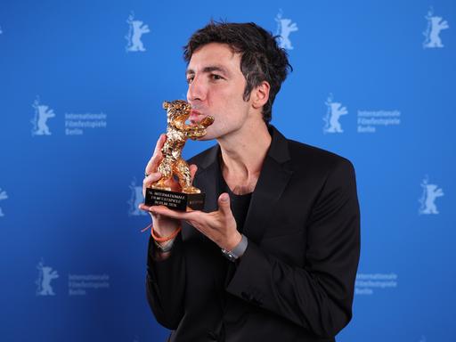 Ilker Catak küsst auf der Bühne der Berlinale die Statuette des Goldenen Bären.
