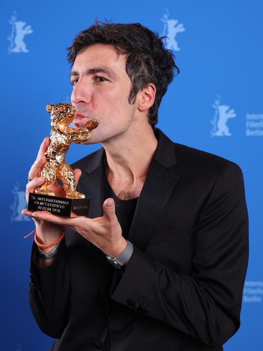 Ilker Catak küsst auf der Bühne der Berlinale die Statuette des Goldenen Bären.