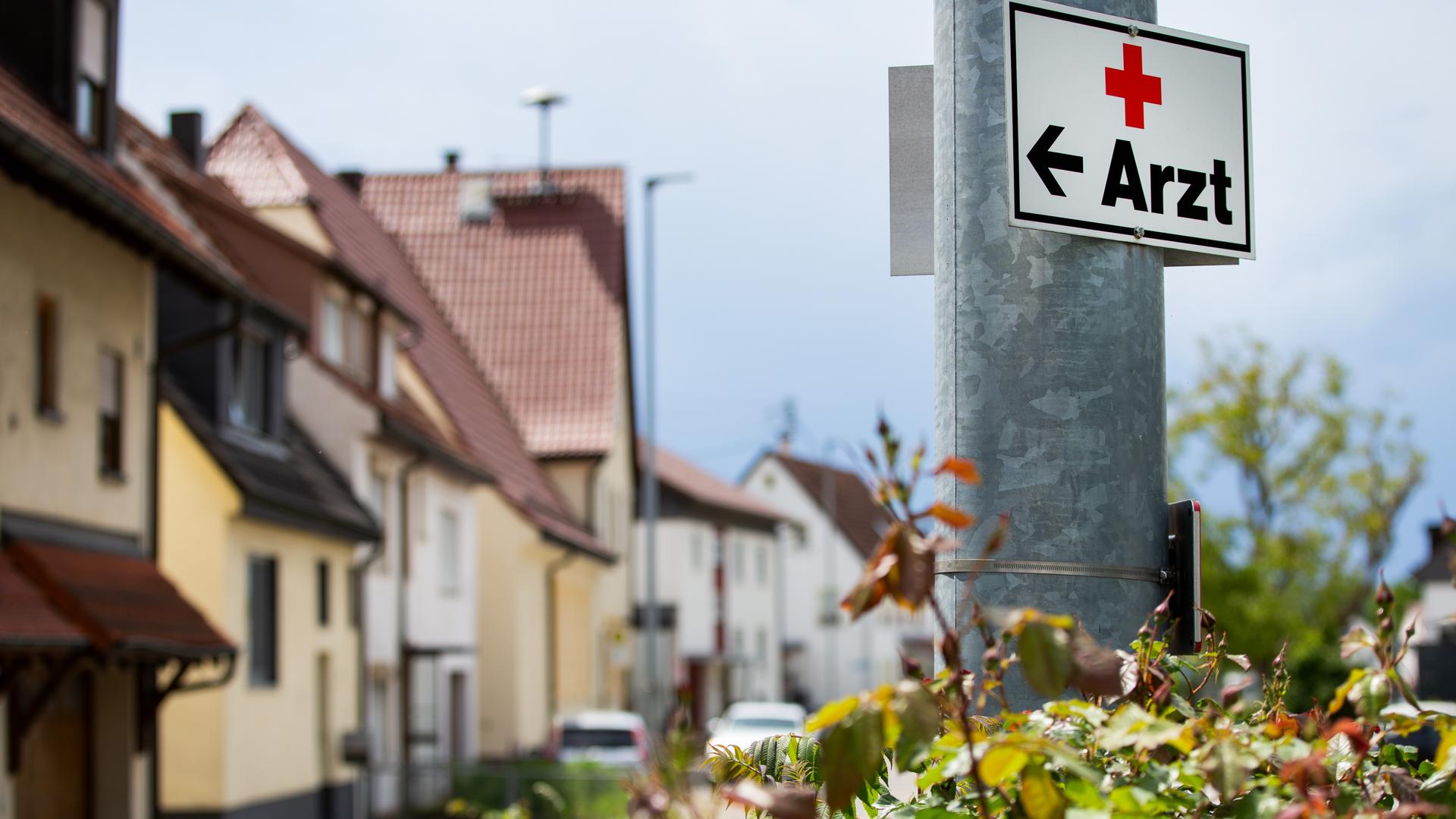 Ein Schild mit der Aufschrift "Arzt" hängt an einer Straßenlaterne. Ein Schild mit der Aufschrift "Arzt" hängt an einer Straßenlaterne.