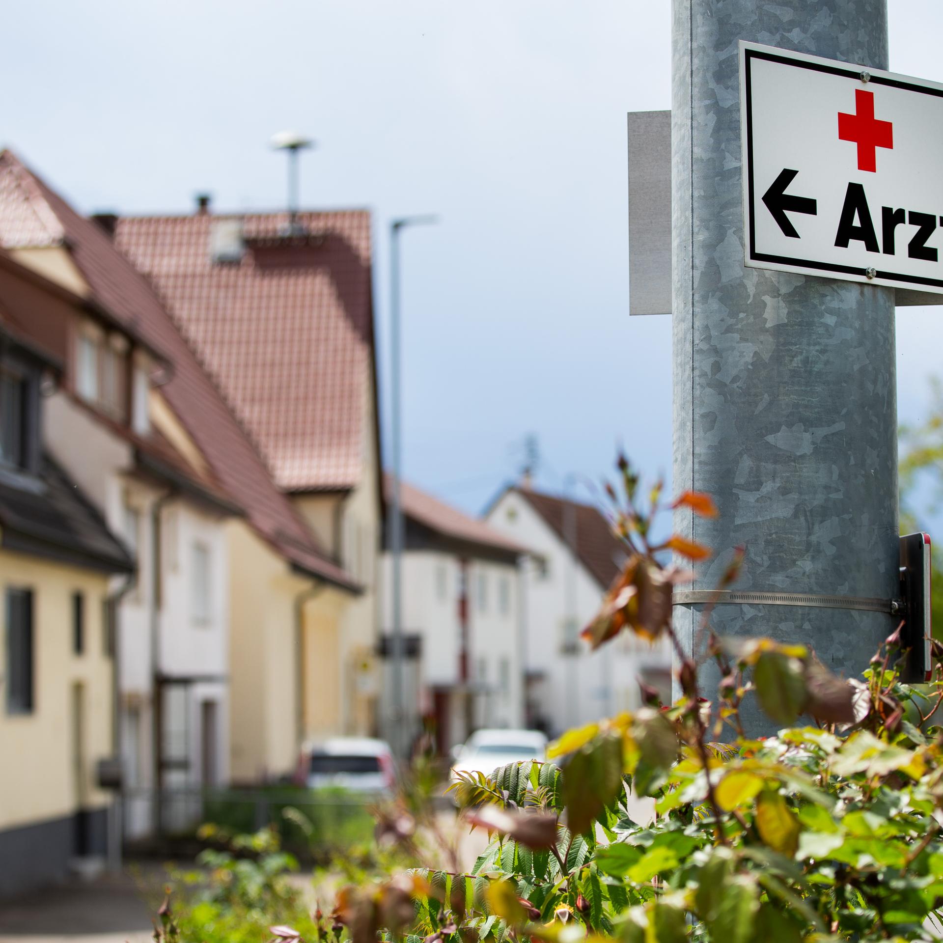 Ein Schild mit der Aufschrift "Arzt" hängt an einer Straßenlaterne.