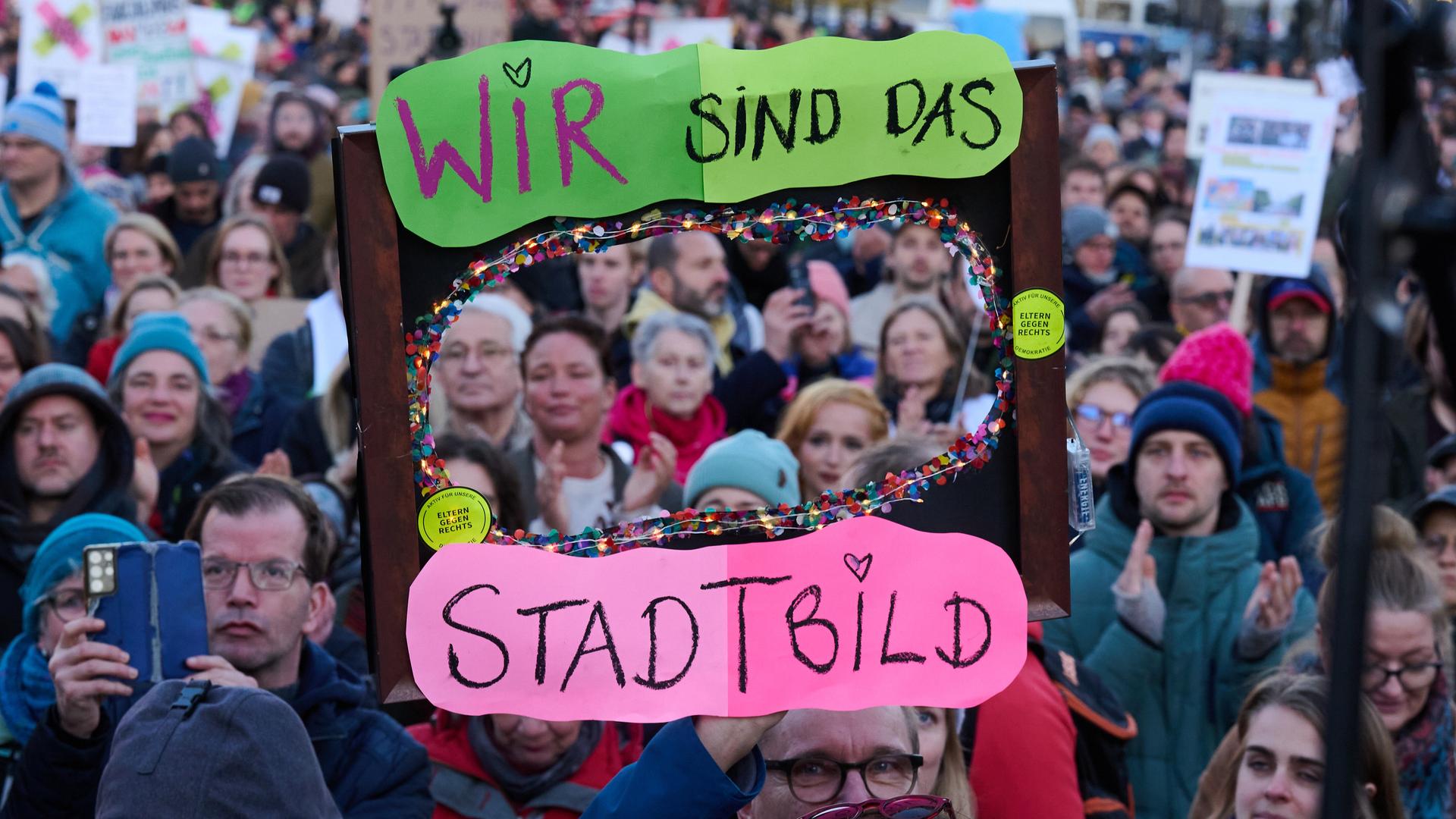 „Wir sind das Stadtbild“ steht auf einem Plakat, das ein Demonstrant vor dem Brandenburger Tor hält. Die Demonstration unter dem Motto «Brandmauer hoch! Wir sind das Stadtbild» bezieht sich auf eine Äußerung von Merz zur Migrationspolitik.