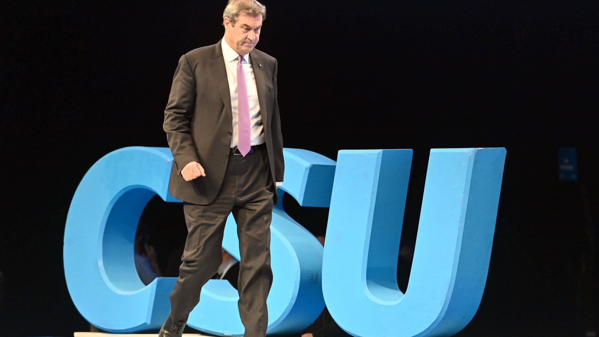 Der bayerische Ministerpräsident und CSU-Vositzende Markus Söder geht auf einer Bühne an einem großen blauen Logo mit den Buchstaben CSU vorbei
