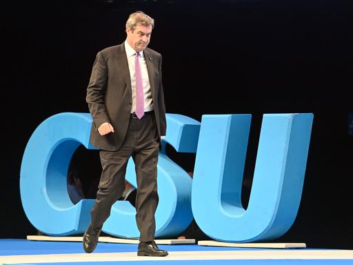 Der bayerische Ministerpräsident und CSU-Vositzende Markus Söder geht auf einer Bühne an einem großen blauen Logo mit den Buchstaben CSU vorbei
