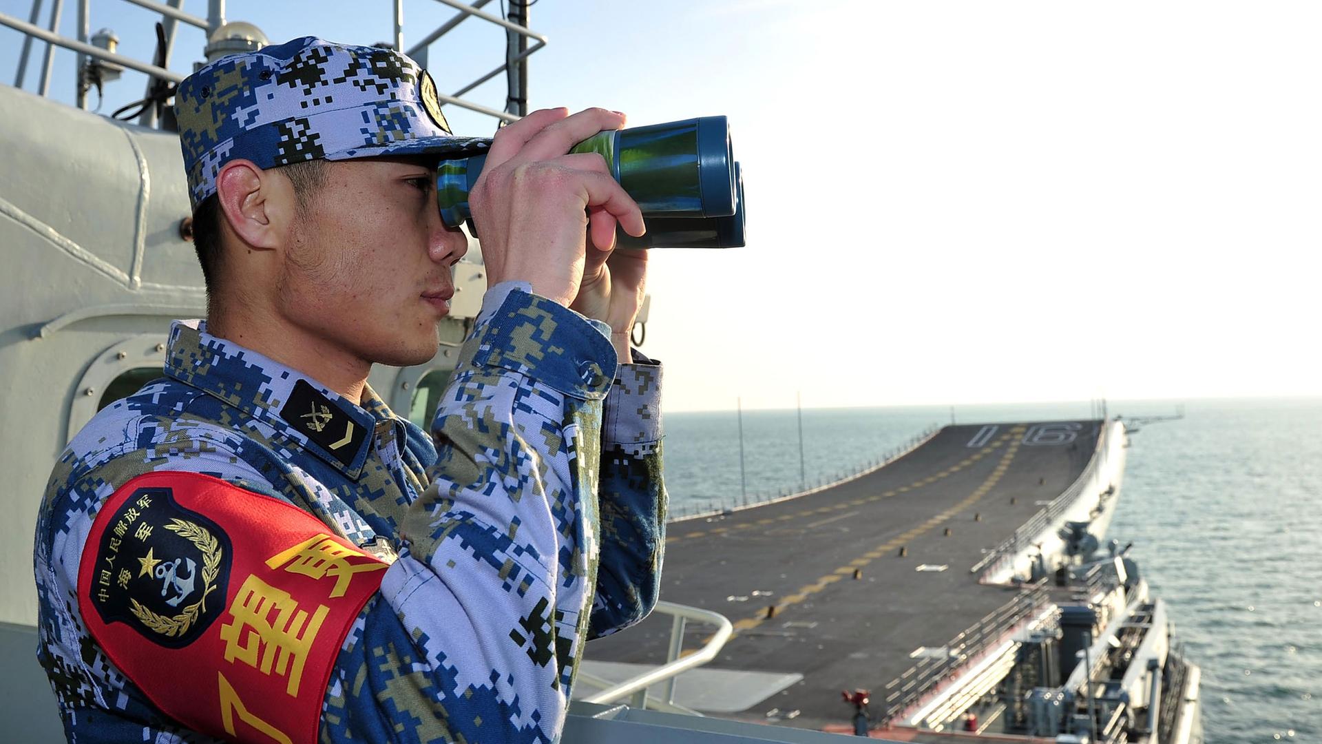 Ein Soldat mit Fernglas an Bord des chinesischen Flugzeugträgers Liaoning.